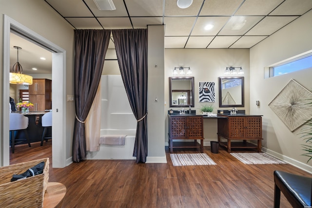 full bathroom featuring wood finished floors, shower / bath combo with shower curtain, baseboards, visible vents, and double vanity