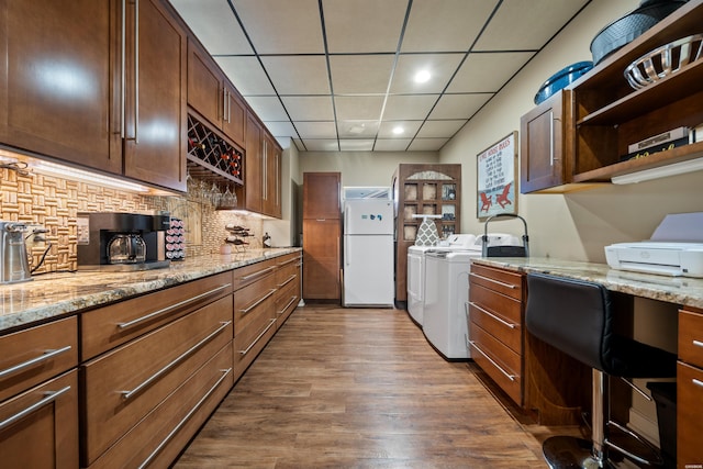 kitchen with tasteful backsplash, open shelves, dark wood-style floors, freestanding refrigerator, and washing machine and dryer