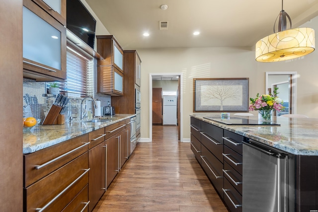 kitchen with light stone counters, a sink, wood finished floors, black electric cooktop, and visible vents