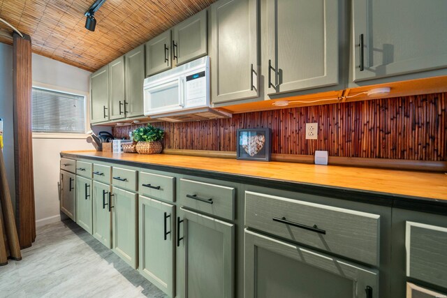 kitchen with green cabinets, wooden counters, white microwave, and baseboards