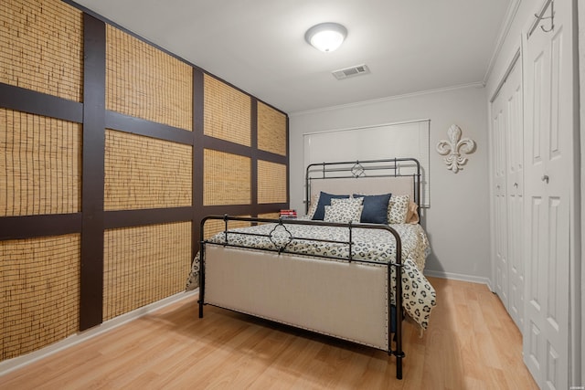 bedroom featuring crown molding, baseboards, visible vents, a closet, and wood finished floors