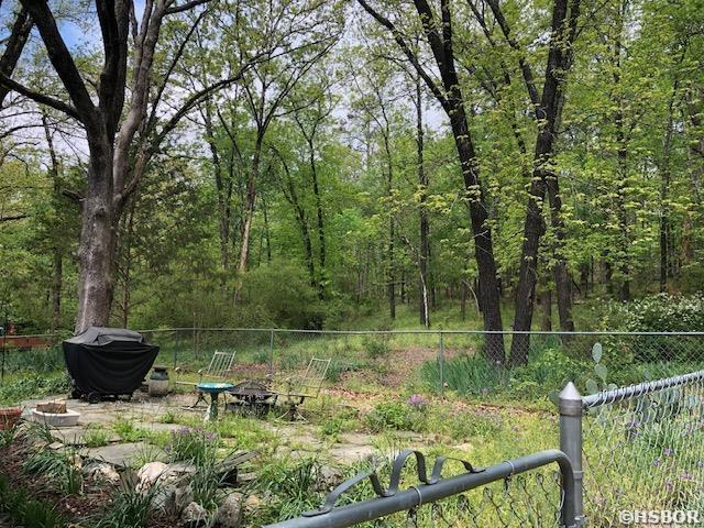 view of yard with a forest view and fence