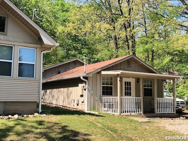 view of property exterior featuring a yard, board and batten siding, and covered porch