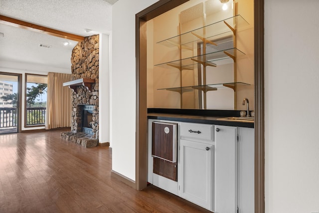 724 Weston Rd Unit Q-4, Hot Springs, AR 71913 - indoor wet bar featuring beverage cooler, beam ceiling, dark wood-style flooring, a textured ceiling, and a fireplace