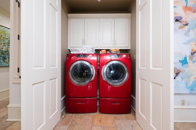 laundry area featuring stone finish flooring, separate washer and dryer, and cabinet space