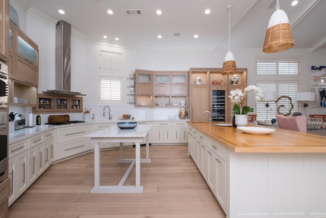 kitchen featuring a spacious island, plenty of natural light, open shelves, and wall chimney exhaust hood