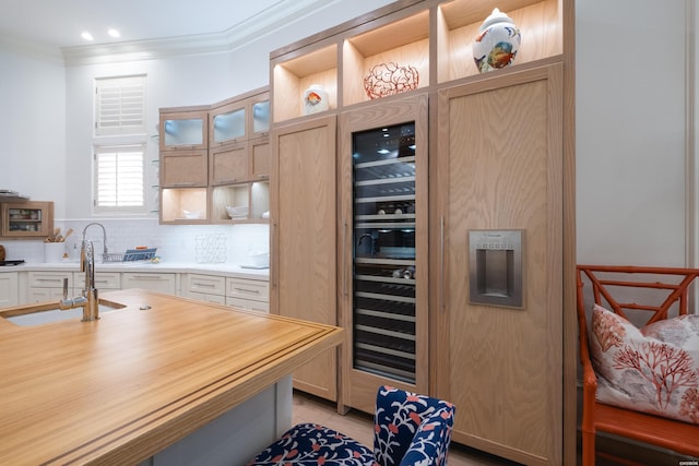 kitchen with crown molding, glass insert cabinets, a sink, and tasteful backsplash