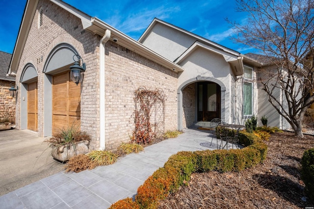 exterior space with brick siding, driveway, and an attached garage
