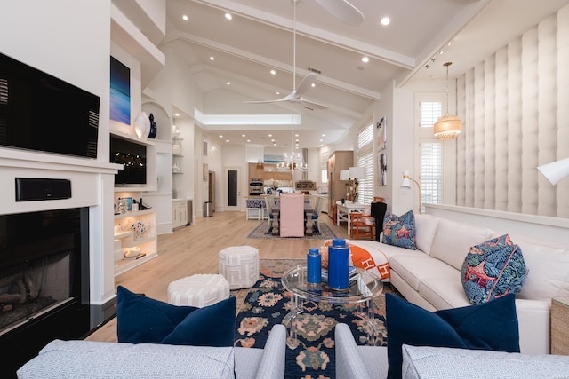 living area featuring a fireplace with raised hearth, beam ceiling, recessed lighting, light wood finished floors, and a ceiling fan