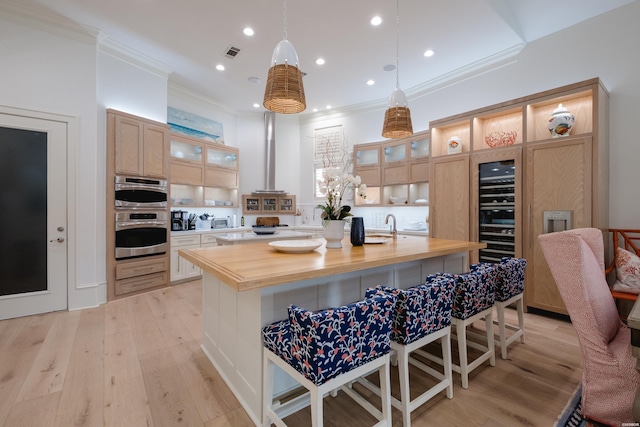 kitchen featuring crown molding, a spacious island, visible vents, light wood-style floors, and a kitchen bar