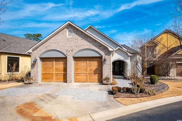 view of front of house featuring a garage, brick siding, driveway, and roof with shingles