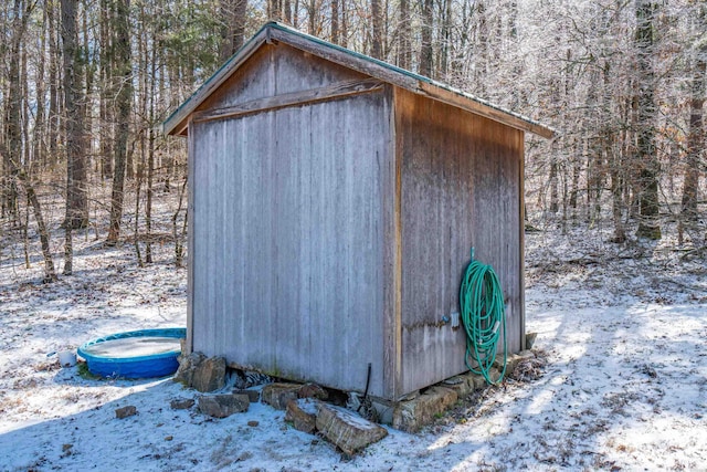 snow covered structure featuring a shed and an outbuilding