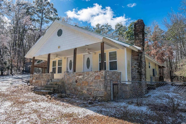 view of front of property with a ceiling fan, covered porch, fence, and a chimney