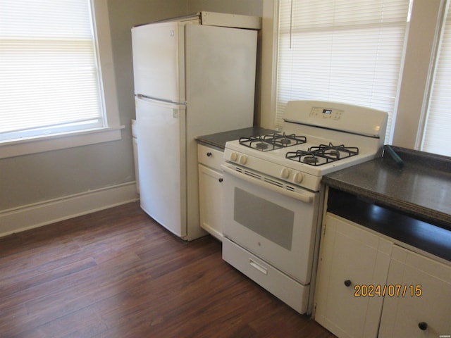 kitchen with white gas stove, dark wood-type flooring, white cabinets, baseboards, and dark countertops