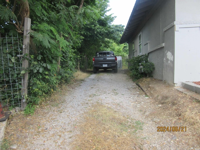 view of side of property with gravel driveway and stucco siding