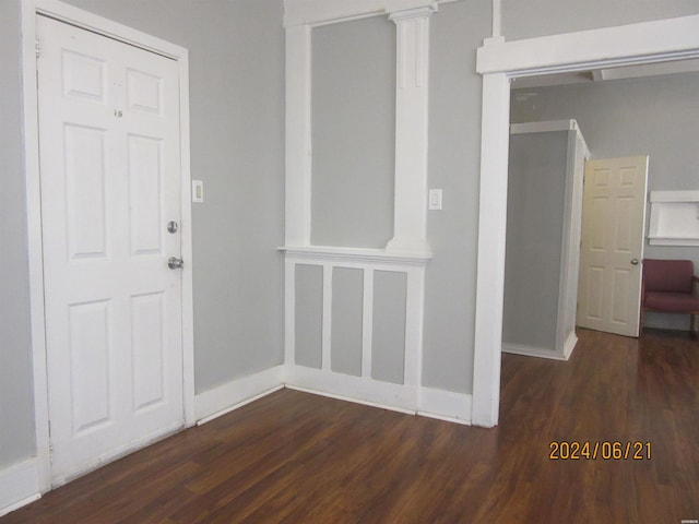 interior space with ornate columns, baseboards, and dark wood finished floors