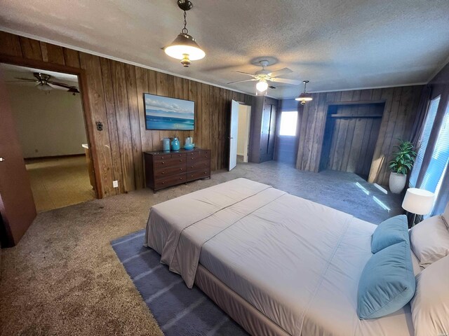 carpeted bedroom with a textured ceiling, wooden walls, a ceiling fan, and crown molding