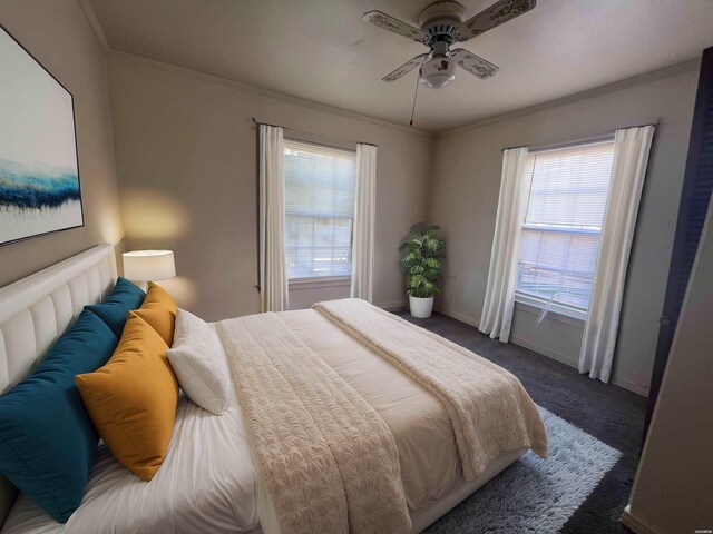 bedroom with dark colored carpet, ornamental molding, a ceiling fan, and baseboards