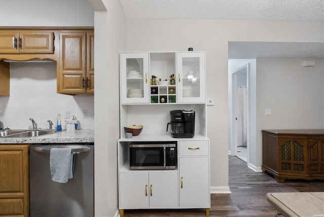 kitchen with a sink, light countertops, appliances with stainless steel finishes, dark wood-style floors, and brown cabinetry