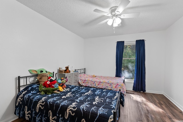 bedroom with dark wood-style floors, ceiling fan, baseboards, and a textured ceiling