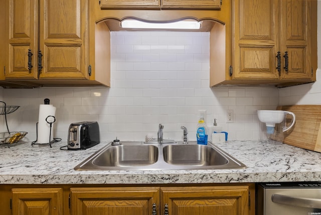 kitchen featuring brown cabinets, dishwasher, light countertops, and a sink