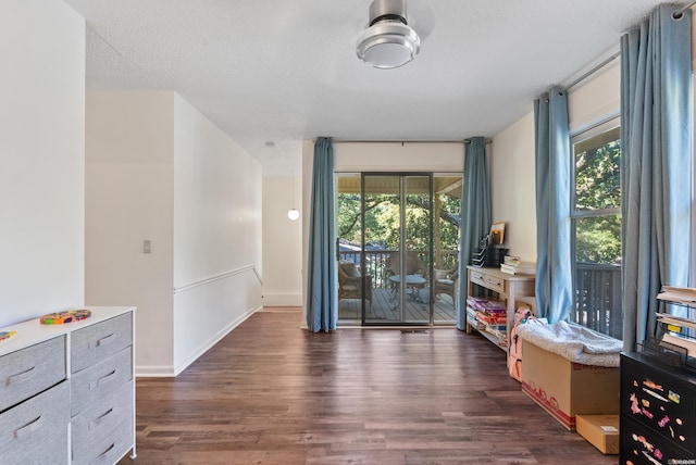 spare room featuring plenty of natural light, a textured ceiling, baseboards, and dark wood-type flooring