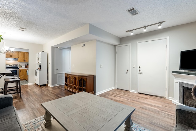 living area featuring a textured ceiling, a tile fireplace, visible vents, and light wood-style floors