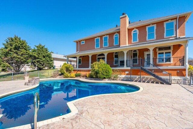 rear view of house featuring stucco siding, a patio, a fenced in pool, and fence