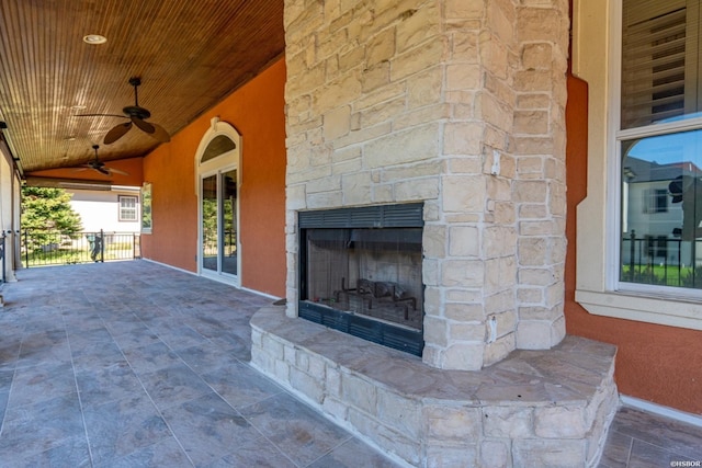 view of patio with an outdoor stone fireplace and ceiling fan