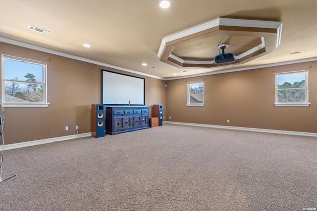 home theater room featuring carpet, visible vents, baseboards, a tray ceiling, and crown molding