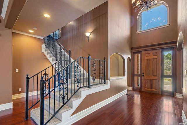 entryway with baseboards, recessed lighting, wood finished floors, arched walkways, and a notable chandelier