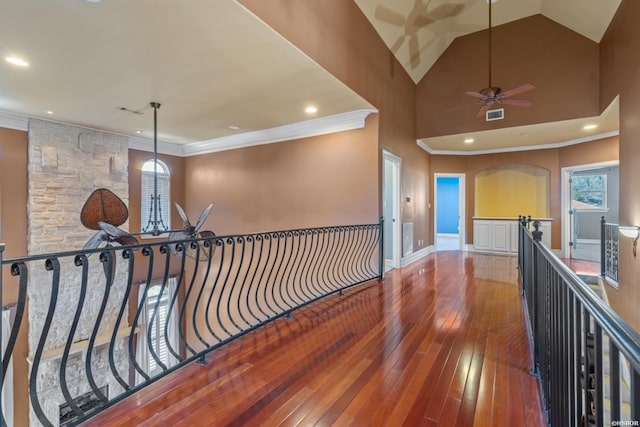 hall with visible vents, an upstairs landing, high vaulted ceiling, hardwood / wood-style floors, and crown molding