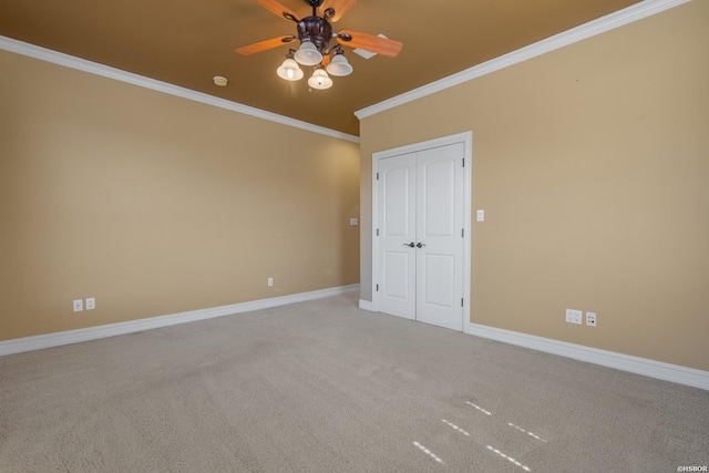 carpeted spare room featuring ceiling fan, baseboards, and ornamental molding