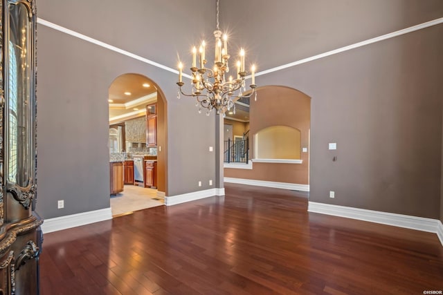 interior space featuring arched walkways, crown molding, baseboards, and wood finished floors