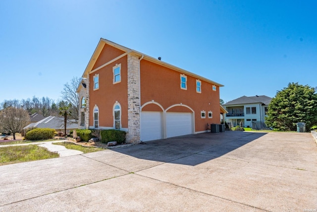 view of property exterior featuring stucco siding, driveway, central AC, and a garage