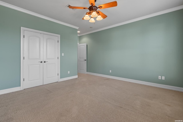 unfurnished bedroom with a closet, baseboards, carpet, and crown molding