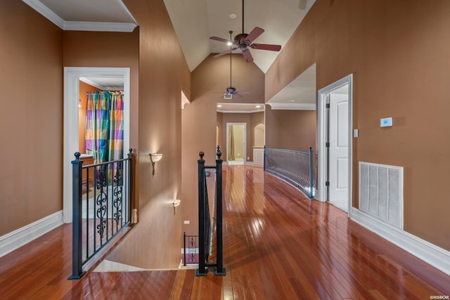 hall featuring visible vents, baseboards, an upstairs landing, hardwood / wood-style flooring, and high vaulted ceiling