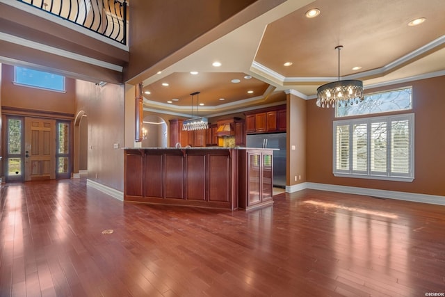 kitchen with a tray ceiling, an inviting chandelier, and dark wood-style floors