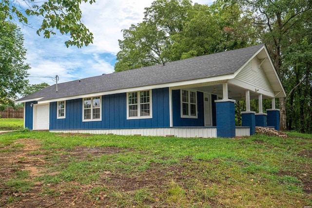 view of side of home featuring a yard, a porch, board and batten siding, and roof with shingles