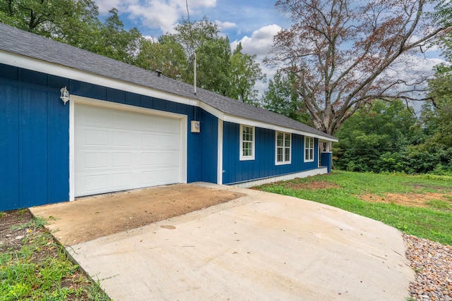 view of front of property featuring driveway, a garage, an outbuilding, and roof with shingles