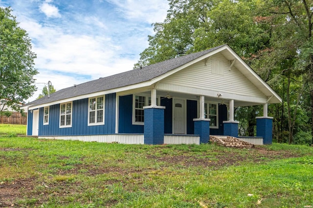 view of front of house featuring board and batten siding, a front yard, and covered porch