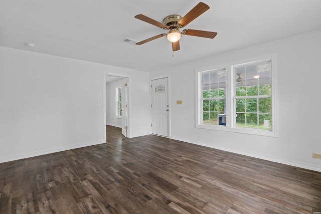 empty room with dark wood-style floors, ceiling fan, visible vents, and baseboards