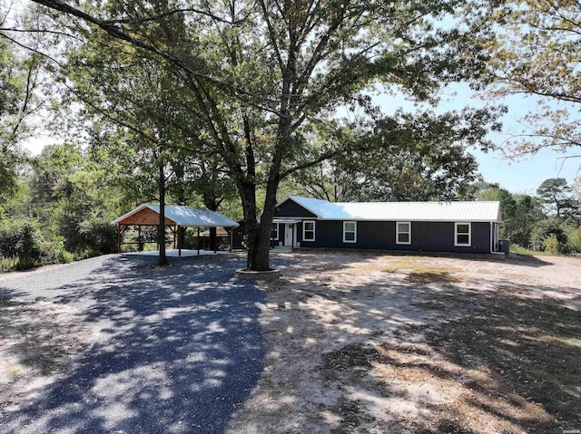 single story home with gravel driveway, metal roof, and a carport