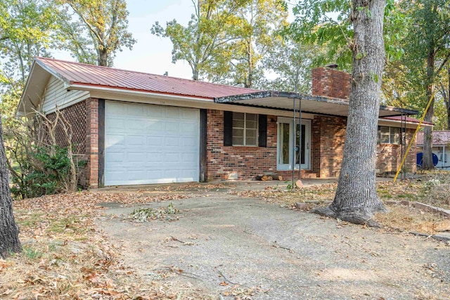 view of front of house featuring a garage, metal roof, brick siding, and a chimney