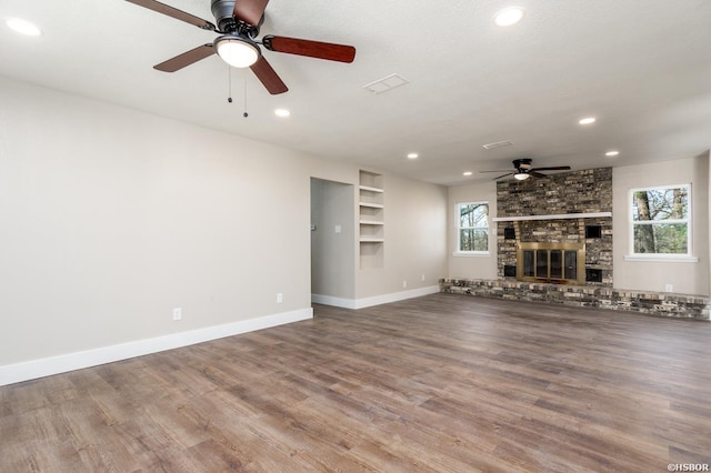 unfurnished living room with a large fireplace, baseboards, wood finished floors, and recessed lighting