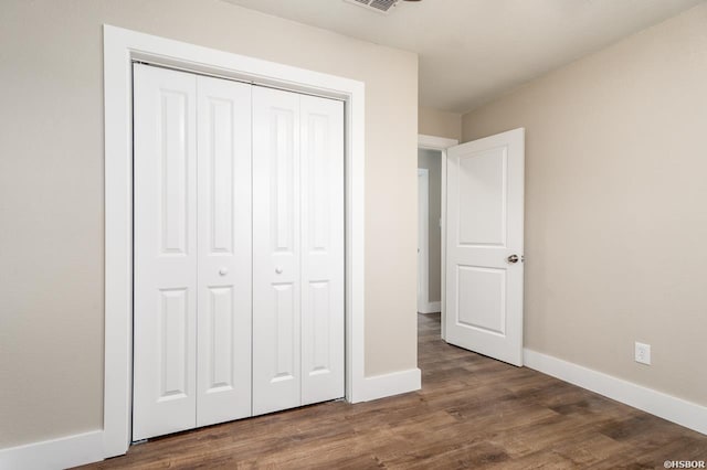 unfurnished bedroom with a closet, wood finished floors, and baseboards