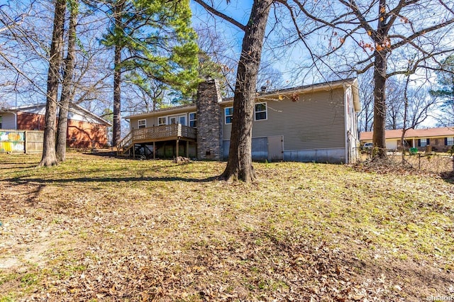 rear view of house with a yard, fence, a chimney, and a wooden deck