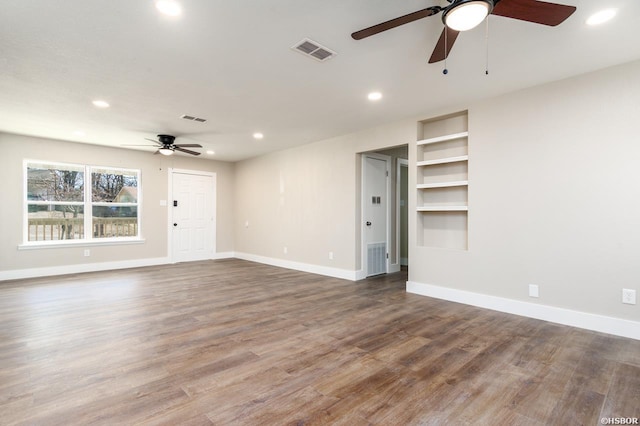 unfurnished living room featuring wood finished floors, visible vents, and baseboards