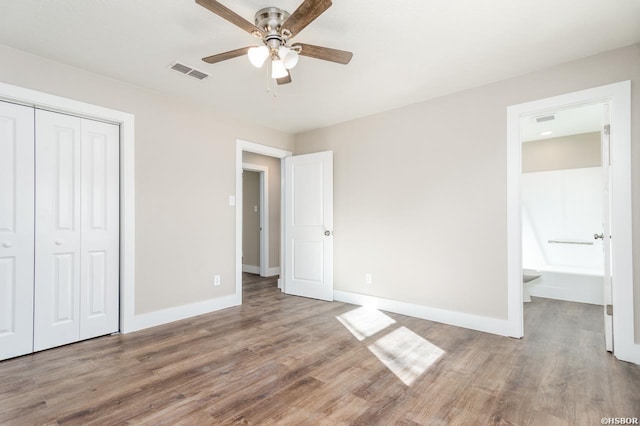 unfurnished bedroom featuring a closet, visible vents, baseboards, and wood finished floors