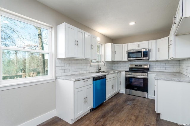 kitchen featuring dark wood finished floors, decorative backsplash, stainless steel appliances, and a sink